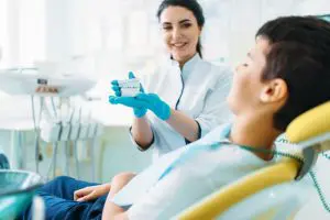female-dentist-shows-dentures-to-little-boy-QL97ED4