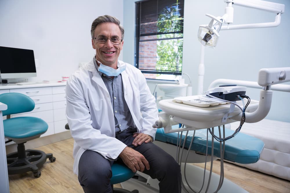 portrait-of-smiling-dentist-sitting-on-chair-76JSMLK (1)
